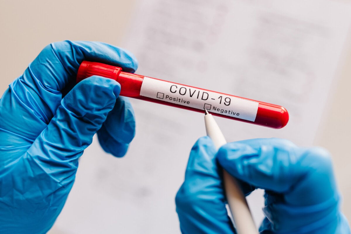 covid 19 text. a hands of doctor, nurse, scientist writes with a pen and confirms the negative result, hold a test tube with biological sample. coronavirus. blood is dont infected. new cases of cure.