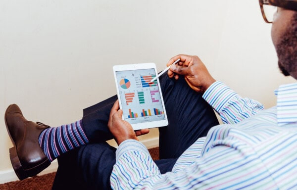 man sitting and using a tablet with stats