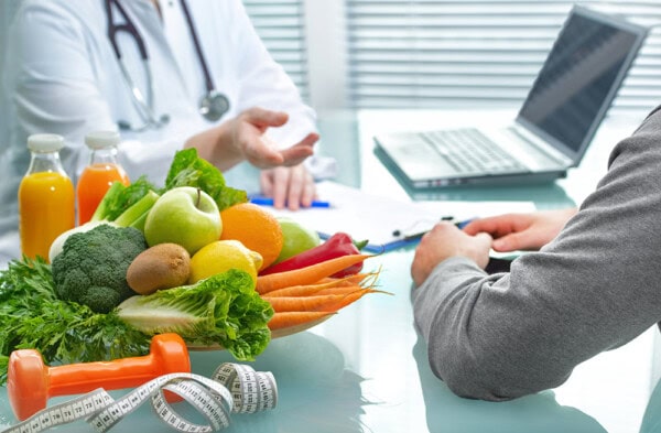 nutritionist is consulting the patient about healthy diet with vegetables and fruits